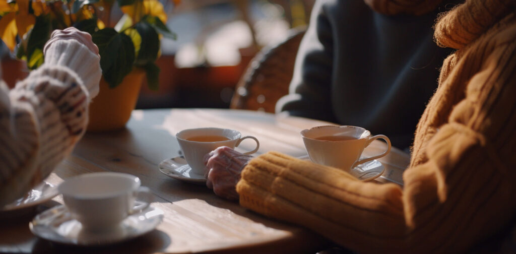 Des personnes sirotent un café dans des tasses en porcelaine sur une table en bois dans une atmosphère détendue.