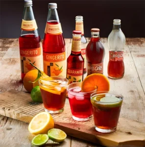 Bicchieri con Gingerito, Guaranito e Molecola serviti con frutta fresca per un aperitivo sostenibile
