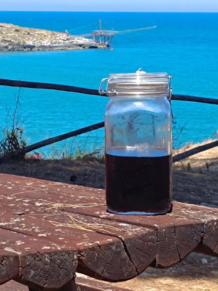 Cold Brew coffee in un vaso bormioli su una spiaggia a vieste con in vista un trabucco