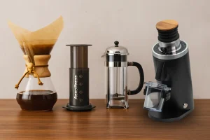 Macinacaffè D54 affiancato da Chemex, Aeropress e French Press su piano in legno: setup ideale per home barista e metodi filtro o cold brew